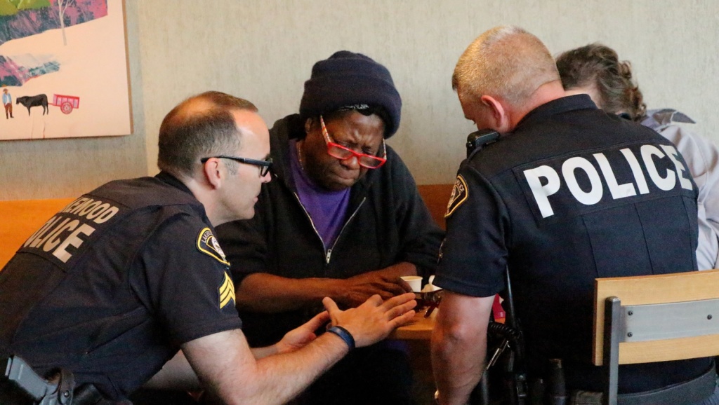 Lakewood Police officers sit at a table with residents during a Coffee with a Cop event