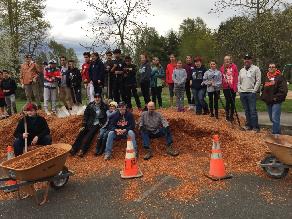 Picture of volunteers on top of mound of wood chips