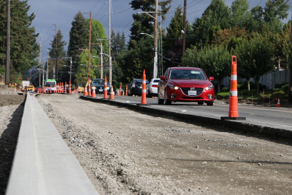 Photo of road construction with orange pillars and cars driving alongside construction