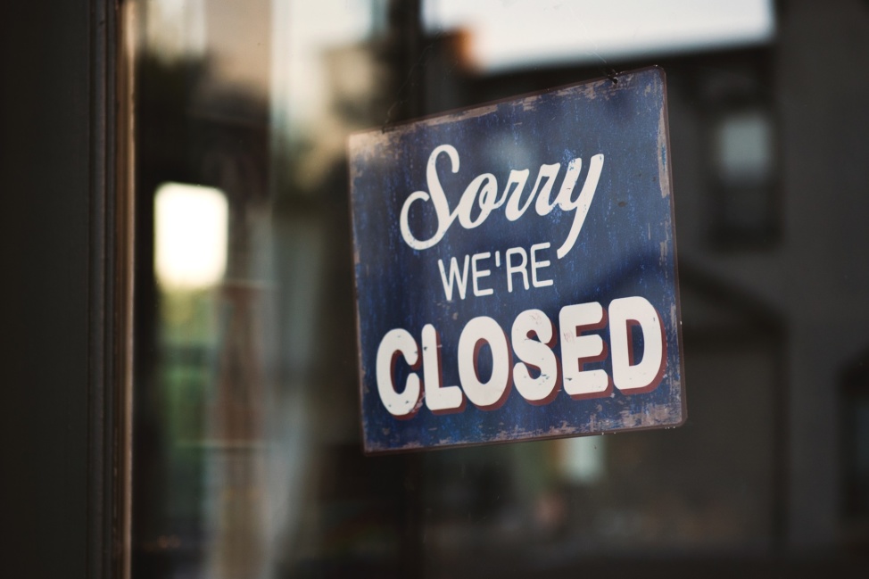 "Sorry we're closed" sign hanging in a glass storefront window