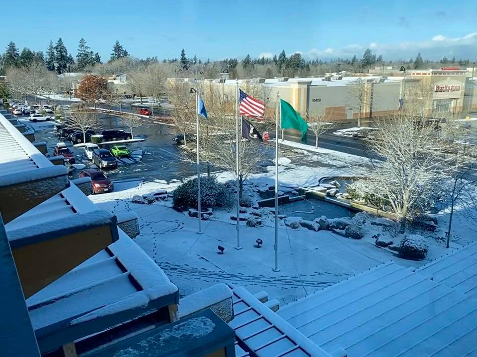 Flag poles at Lakewood City Hall overlooking Towne Center with snow on the ground.