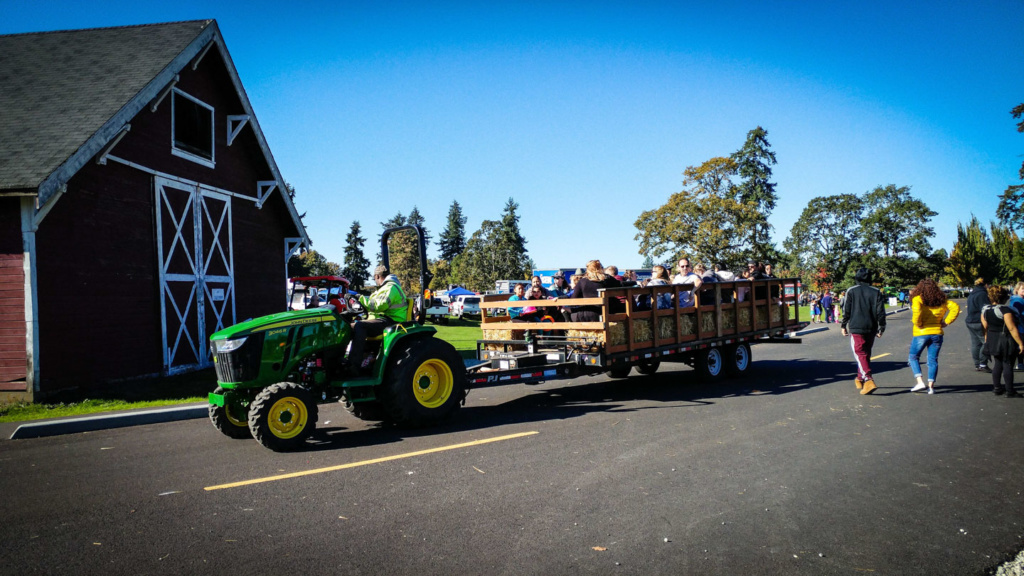 A green tractor pulling a trailer of people.
