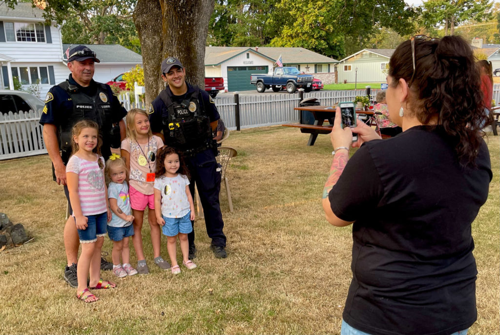 Two officers pose with a group of young siblings at National Night Out. 