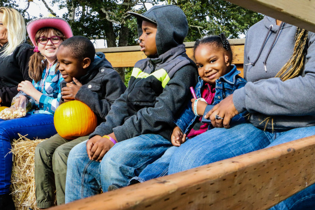 A little girl smiles at the camera while she waits for a hayride to begin at Lakewood Truck & Tractor Day.