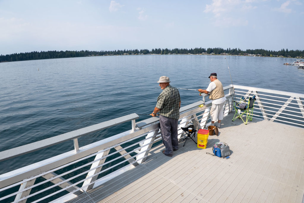 Two older men look at the water on American Lake while casting their fishing lines.