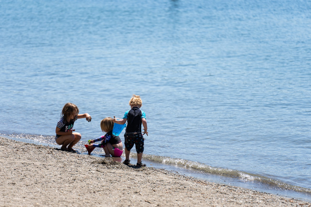 Children play on a beach at American Lake Park. 