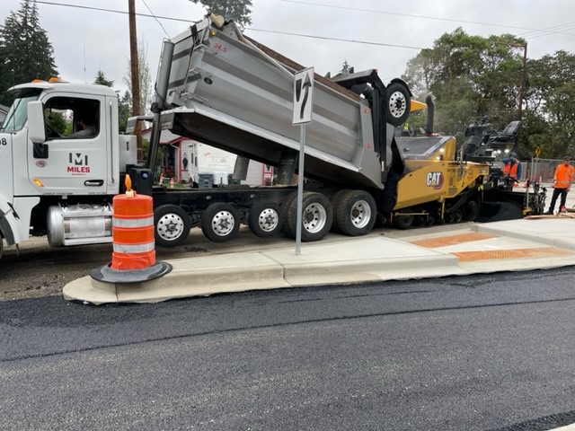 Paving operations with a dump truck and equipment at North Gate Road in Lakewood