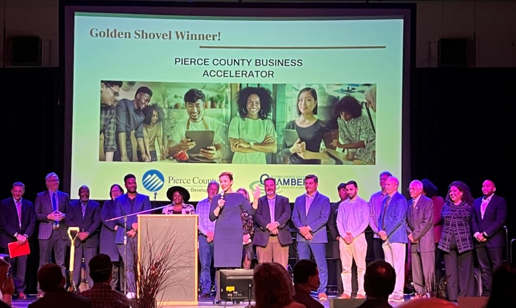 People stand on a stage at the Economic Development Board of Tacoma-Pierce County annual meeting to receive the Golden Shovel award for the creation of the Pierce County Business Accelerator Program.