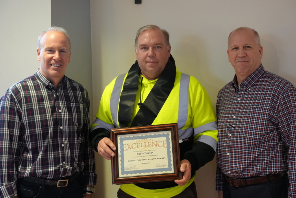 A picture of the Mayor and City Manager awarding Scott Turner an Award of Excellence for outstanding work in Lakewood. 