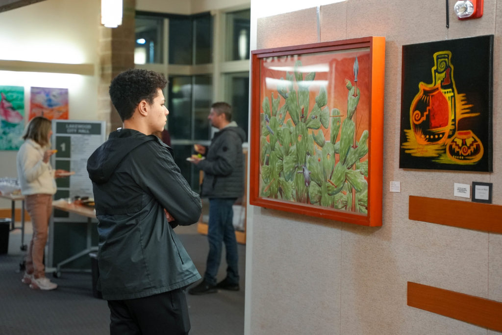 A person enjoys a piece of art hung on the wall of Lakewood City Hall.