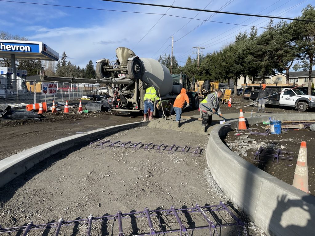 Construction workers shovel pavement around a roundabout in Lakewood Washington.