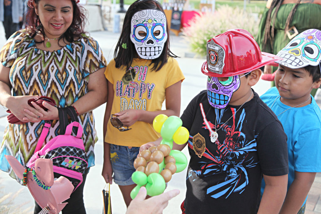Một gia đình đeo mặt nạ đầu lâu bằng đường được trang trí và có tác phẩm nghệ thuật bóng bay từ Lakewood, WA Fiesta de la Familia vào năm 2022.