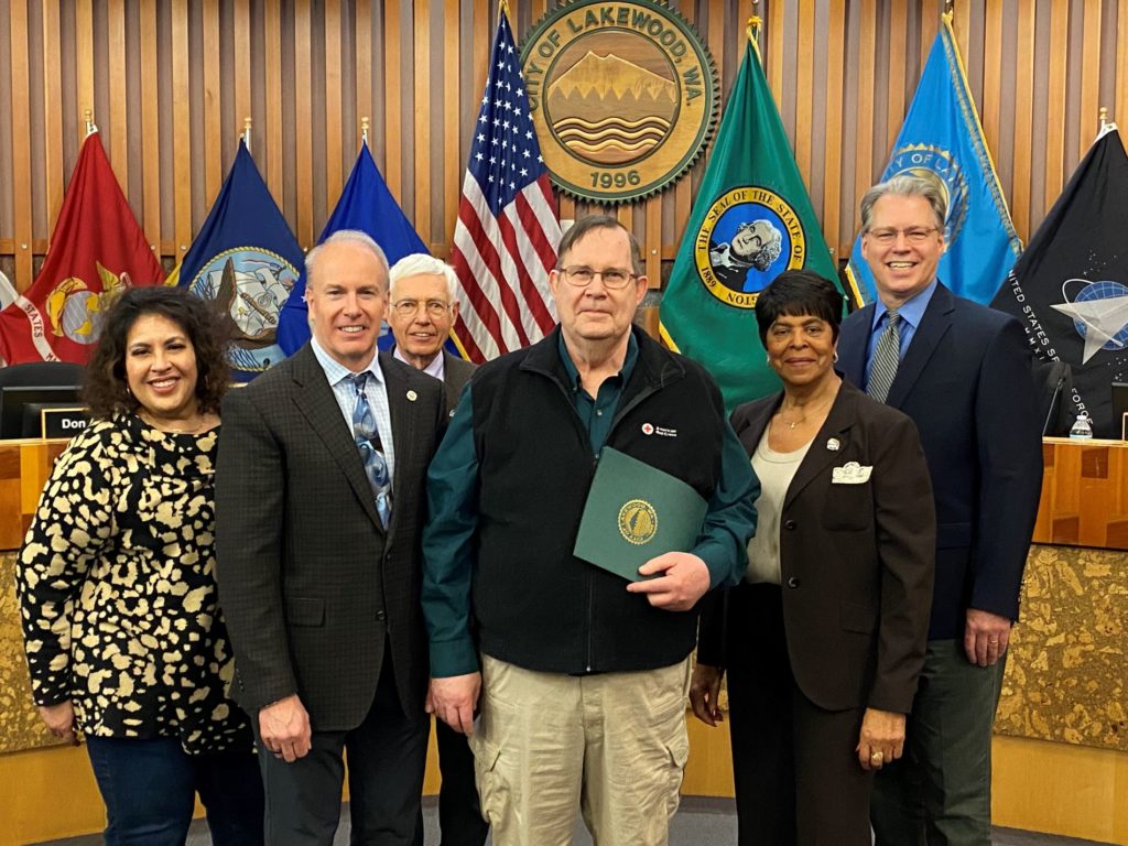 The Lakewood City Council stands with Larry Smith in Council Chambers after presenting him with a proclamation recognizing March as American Red Cross Month in 2023.
