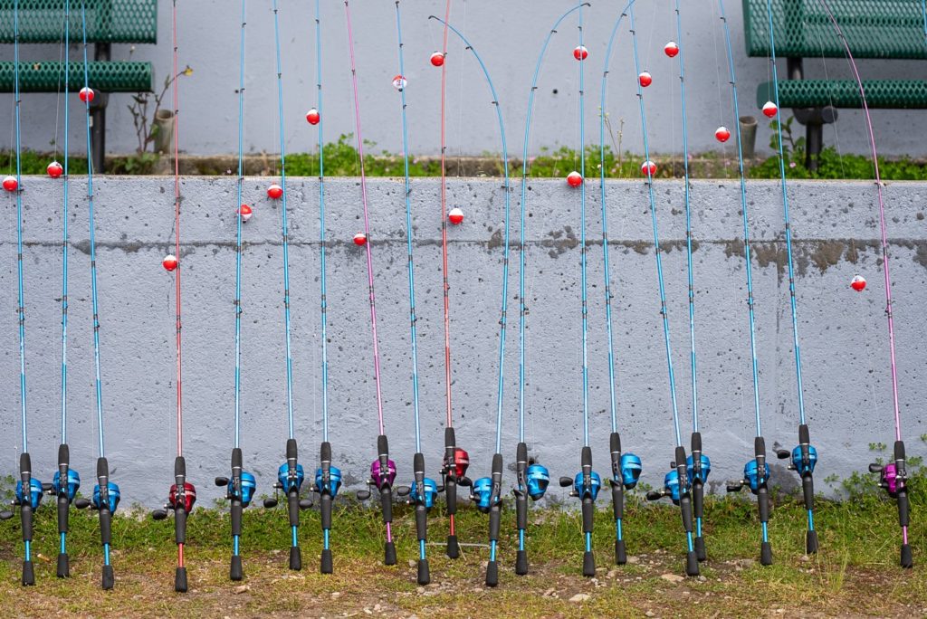 A line up of fishing poles with bobbers on them await children at the Lakewood Kids Fishing Event in Lakewood, WA.