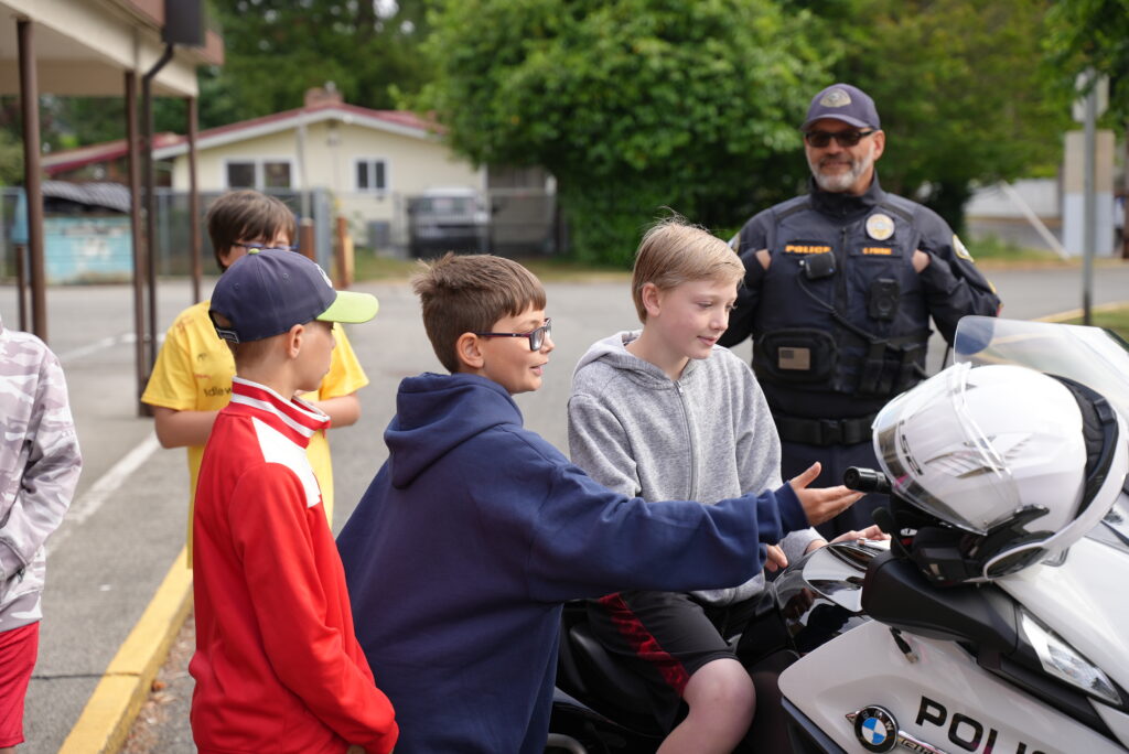 Students get the opportunity to sit on a police motorcycle while a police officer supervises.