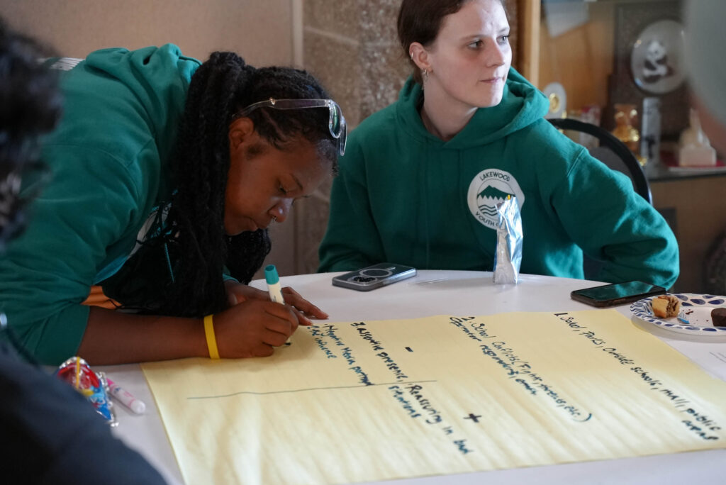 A Lakewood youth council member writes on a large yellow pad with a green marker. 