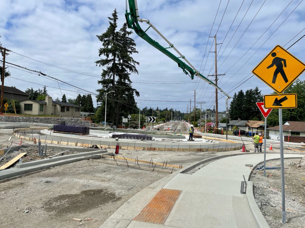 A large piece of machinery sends a tube down to a roundabout on Washington Boulevard to pour concrete in Lakewood, WA.