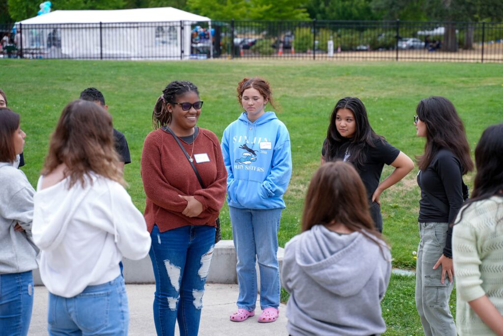 A Youth Council member stands in the middle of a circle formed by other members as they play an icebreaker game. 
