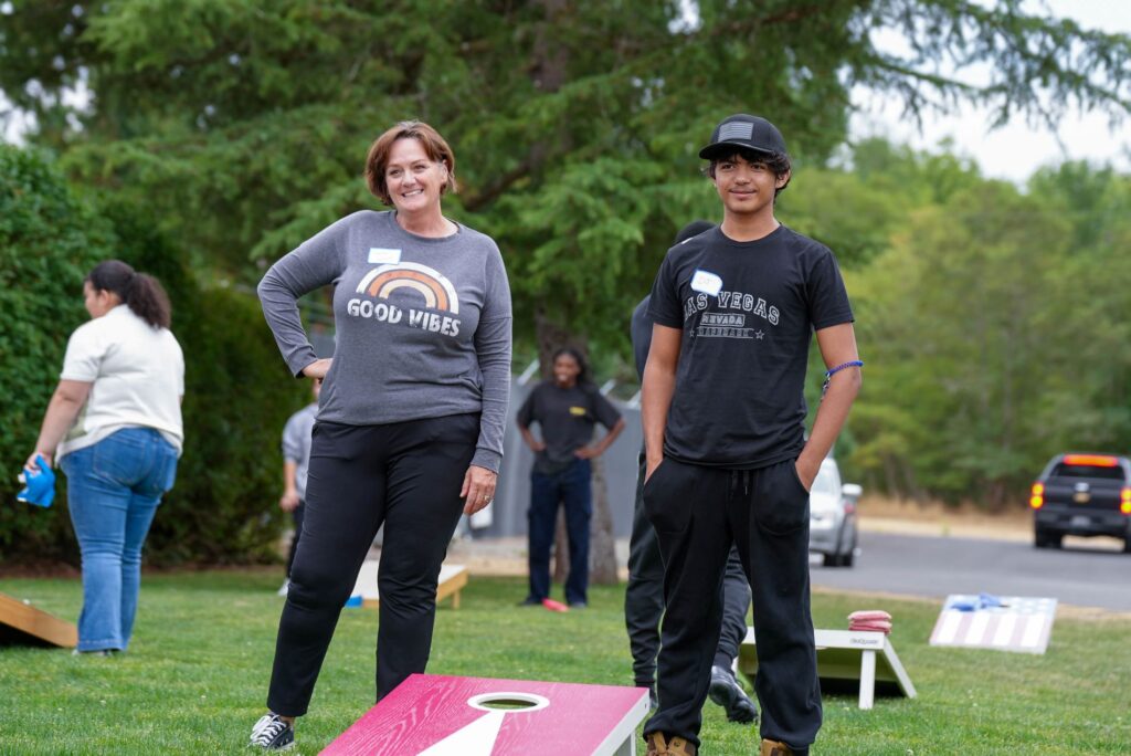 Youth Council leader Shannon Bennett smiles as she plays corn hole with a Youth Council member.