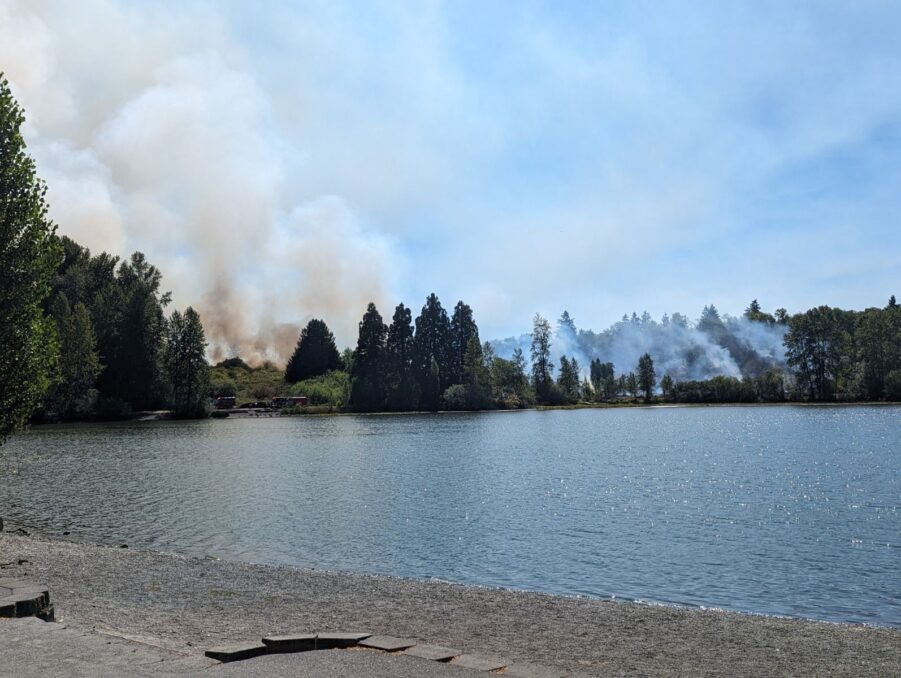 Smoke rises into the sky with Waughop Lake in the foreground at Fort Steilacoom Park on Aug. 16, 2023.