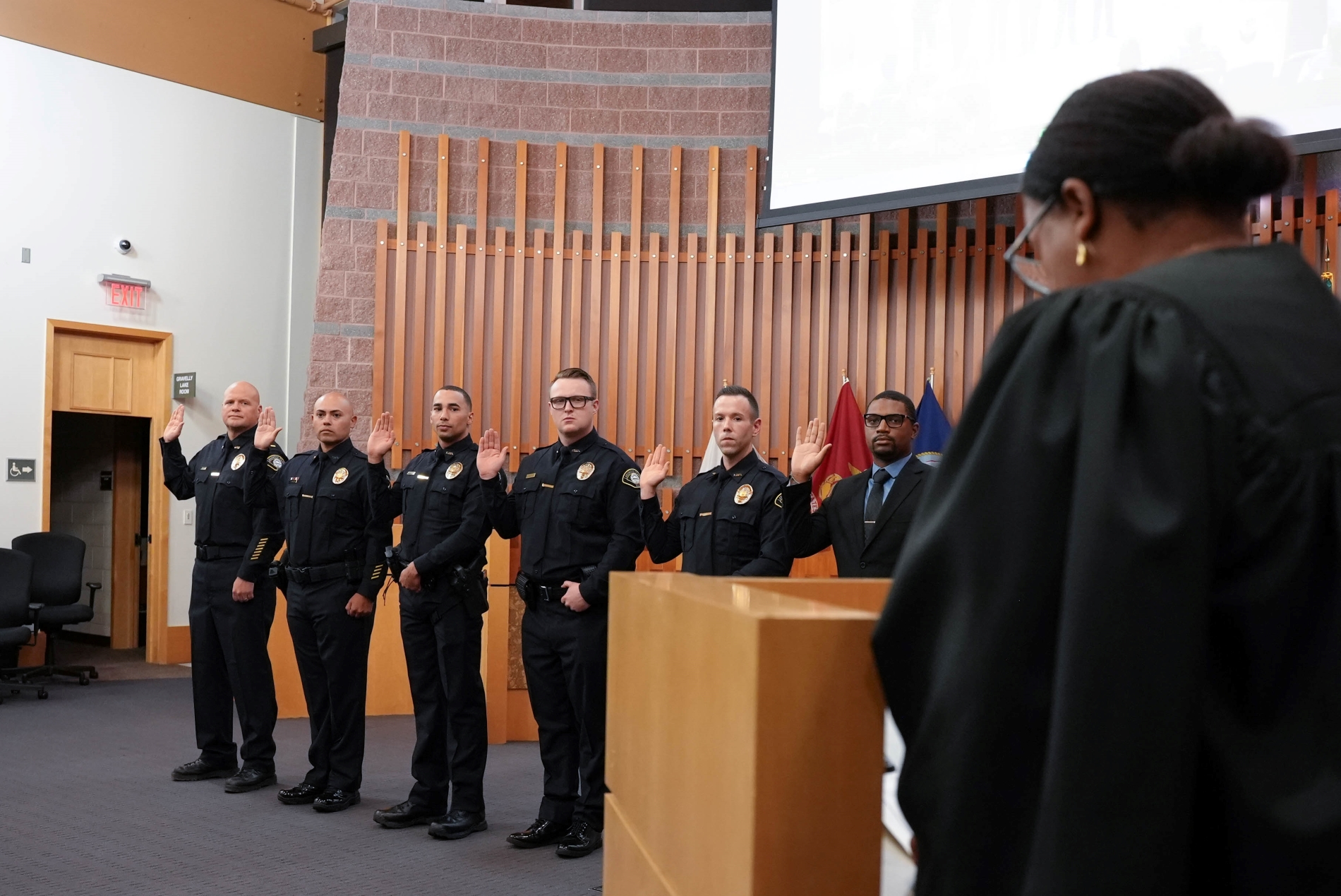 A group of Lakewood Police Officers stand with their hands raised as they are sworn in.