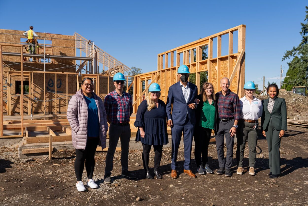 A group of officials including Mayor Jason Whalen stand with Gov. Jay Inslee in Tillicum at a Habitat for Humanity construction site.