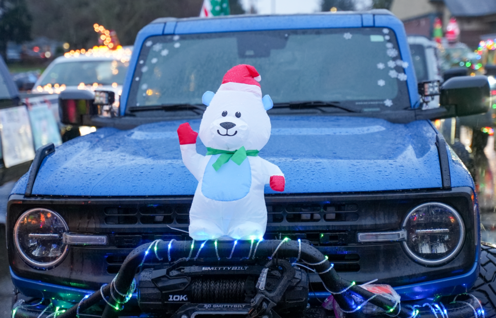 An inflatable white bear with a red santa had waves while fastened to the front of a blue Bronco decorated for the 2023 Lakewood Holiday Parade of Lights