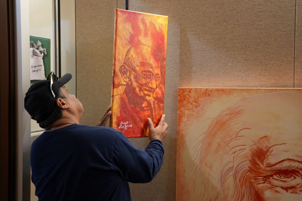 Artist Juan La Torre hangs art in Lakewood City Hall.
