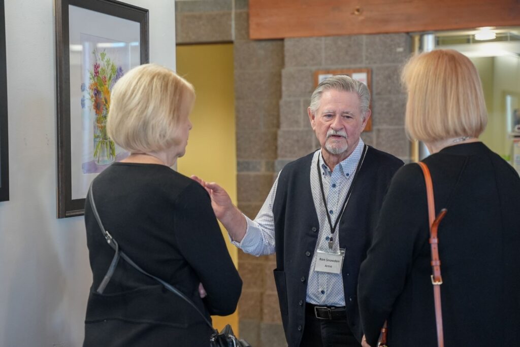 Local artist Ron Snowden speaks with two people during an artist reception at Lakewood City Hall on March 18, 2024.