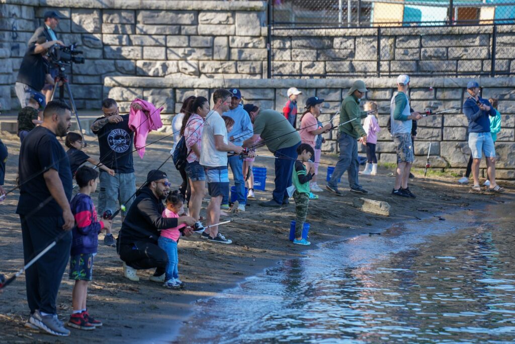 Children and adults fishing on the shoreline of Harry Todd Park in Lakewood in May 2023 for the city's Kid Fishing Event.