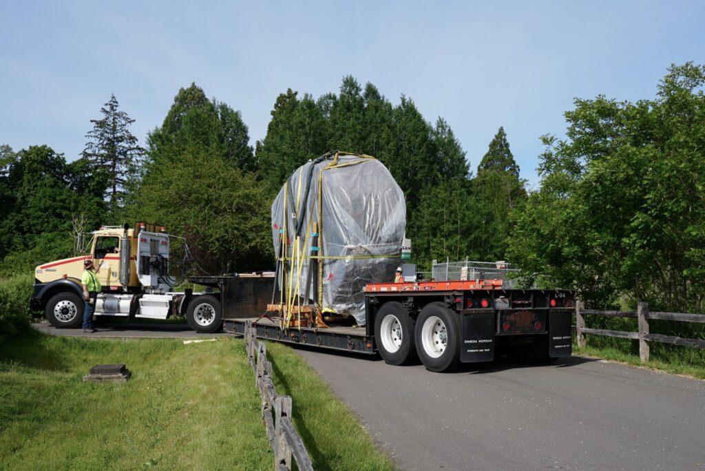 A truck carrying The Big One, a 13-foot-wide Douglas fir round, backs up along a paved trail in Fort Steilacoom Park on June 13, 2024.
