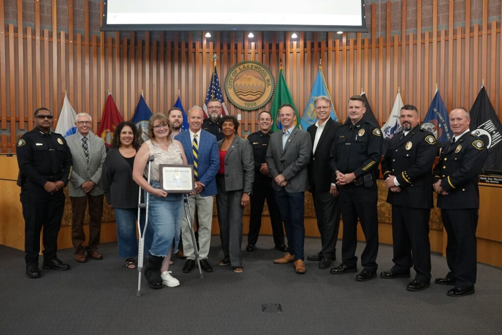 Rebecca Erber, a Lakewood resident, poses with the Lakewood City Council and members of the Lakewood Police Department after being recognized in August 2024 for helping a neighbor during a dog attack