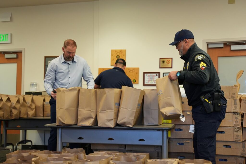 Members of the Lakewood Police Department prepare paper bags filled with food items for the Lakewood Officer's Charity's annual Holiday Meals event.