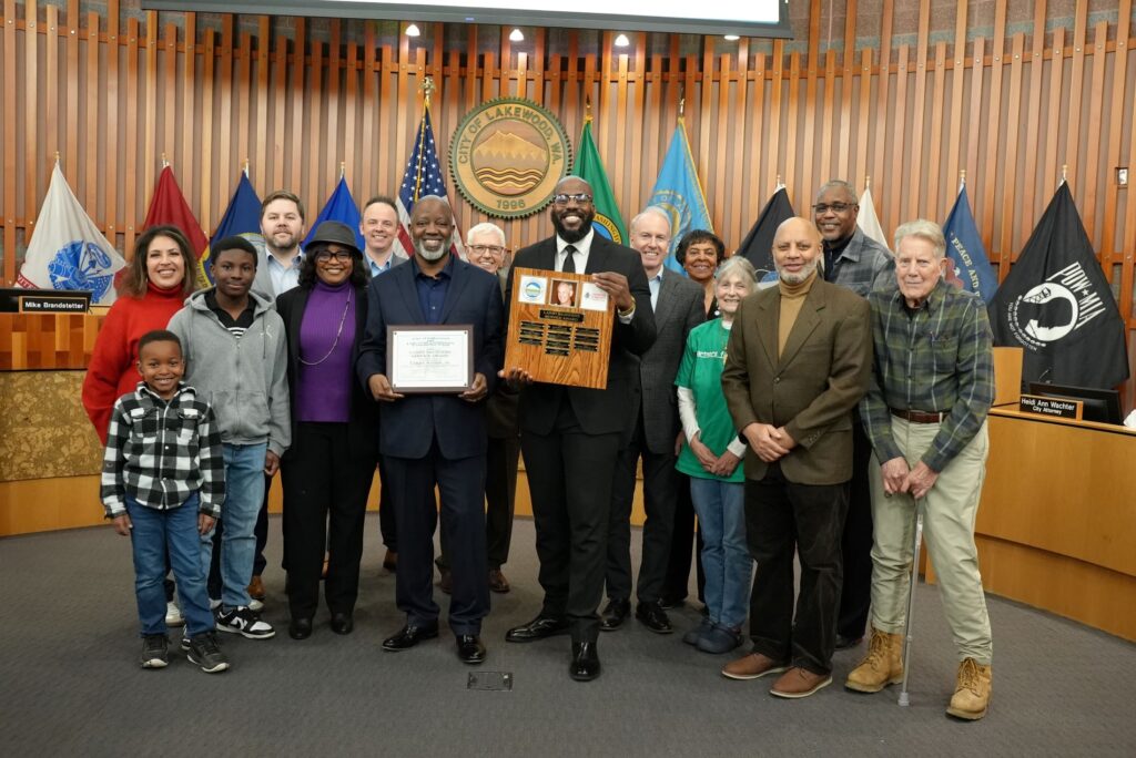 The lakewood City Council poses with Larry Woods, Jr. and his family after giving him the Larry Saunders Service Award