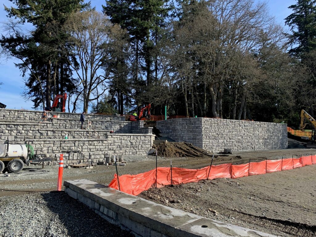 A photo looking at newly built retaining walls in American Lake Park with orange fencing still up.