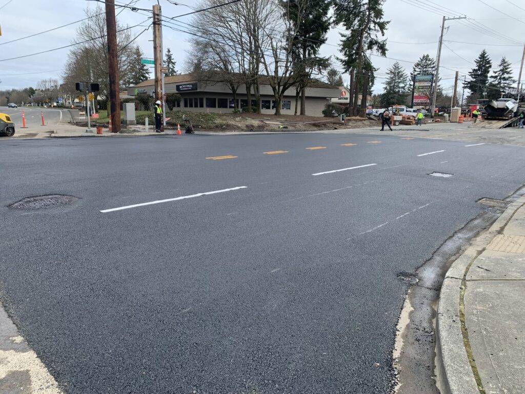 A photo of an intersection of Steilacoom Blvd where a water main broke. The photo shows a newly patched section of road.