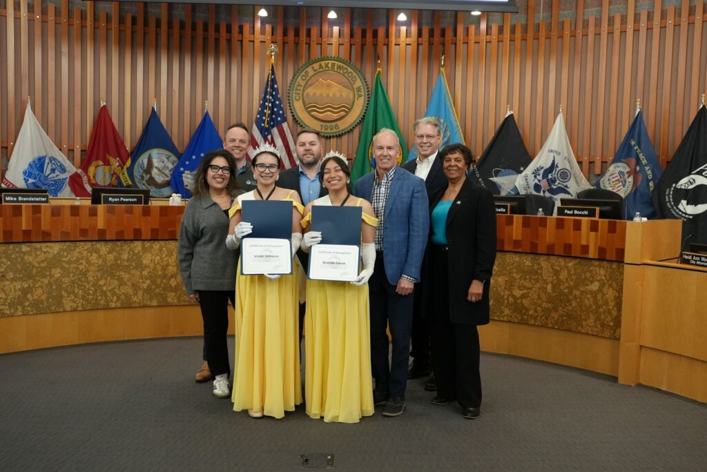 Members of the Lakewood City Council pose with two Daffodil Princesses wearing bright yellow formal ball gowns.