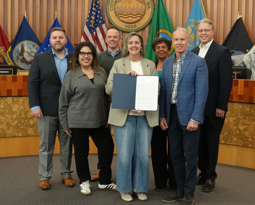 The Lakewood City Council poses for a photo with a person holding up a proclamation declaring April 2025 Sexual Assault Awareness Month.