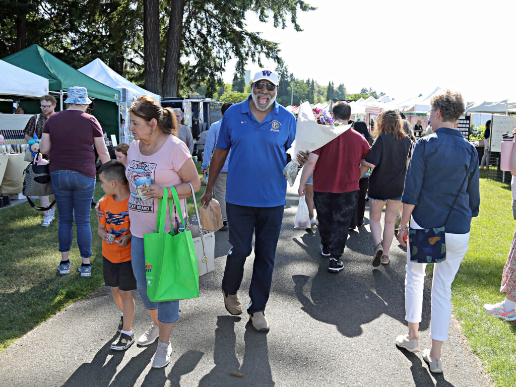 A man smiles widely while holding his groceries at the Farmers Market.