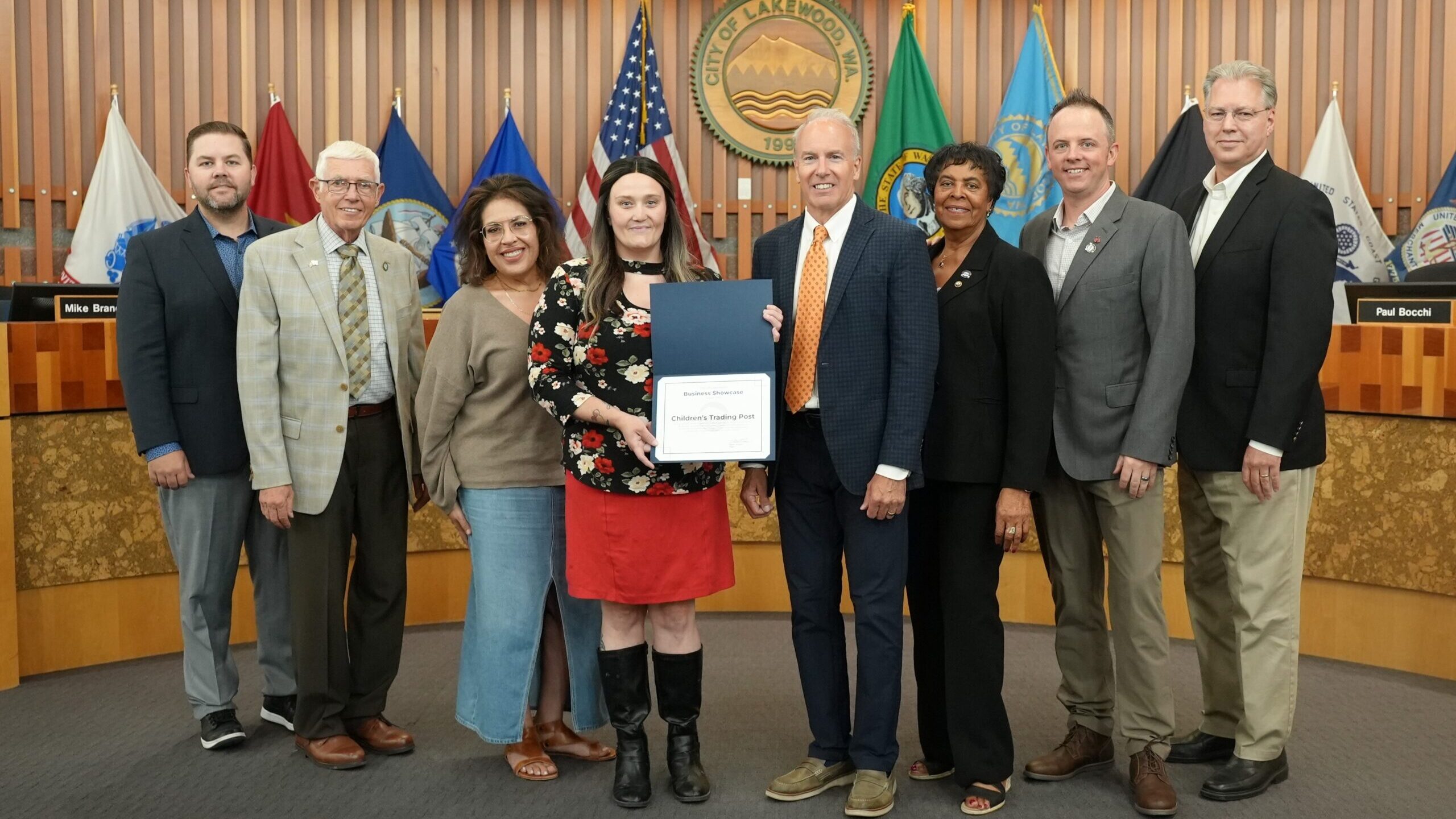 Group of people posed standing in a row with the middle person holding a certificate towards the camera.