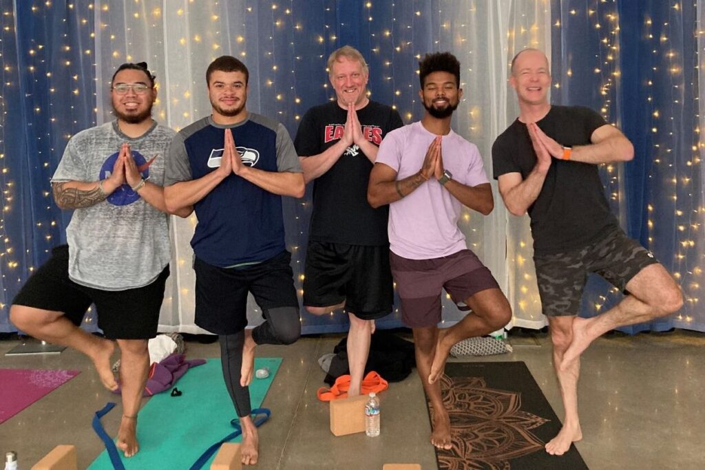 Five men stand in a "tree pose" inside the Lakewood Pavilion for the #LoveLakewood Yoga series.